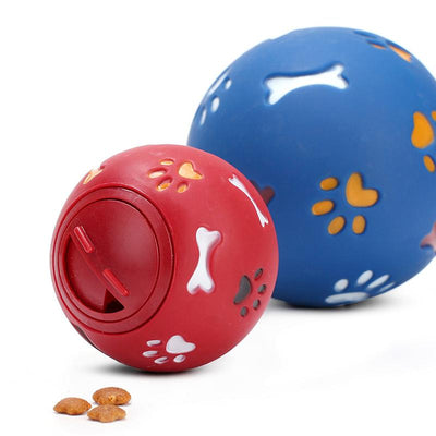 Red rubber pet puzzle ball with white, blue, and orange paw print and bone cutouts, featuring a treat dispenser opening. - Image 8