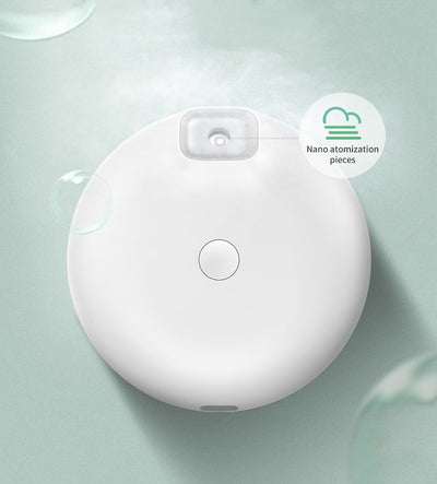 White Baseus car small elephant atomizer actively misting, shown on a wooden surface with a green leaf. - Image 13