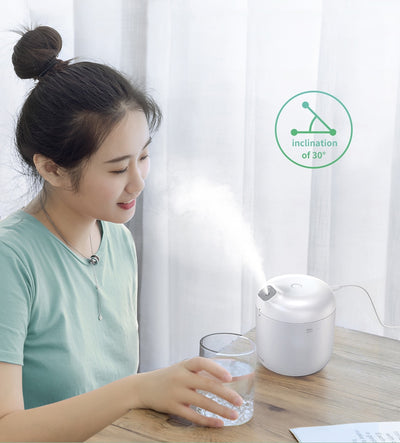White Baseus car small elephant atomizer actively misting, shown on a wooden surface with a green leaf. - Image 17