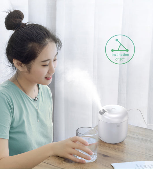 White Baseus car small elephant atomizer actively misting, shown on a wooden surface with a green leaf. - Image 17