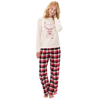 Child wearing a cream long-sleeve pajama top with a reindeer graphic and red, black, and white plaid pajama pants. - Image 8