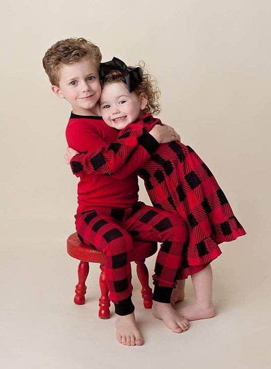 Family of four wearing matching red and black buffalo plaid Christmas pajamas, featuring solid red long-sleeve tops and plaid pants. - Image 14