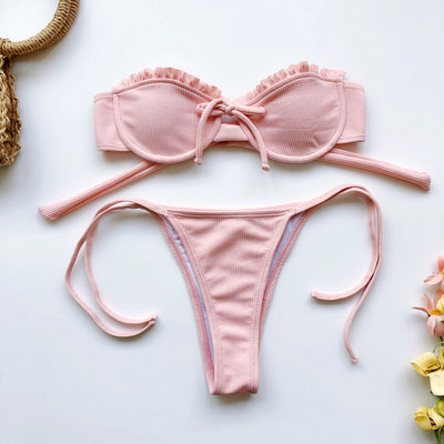 Light pink ribbed bikini set with a strapless ruffled top and high-cut, tie-side bottom on a model. - Image 11