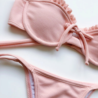 Light pink ribbed bikini set with a strapless ruffled top and high-cut, tie-side bottom on a model. - Image 12