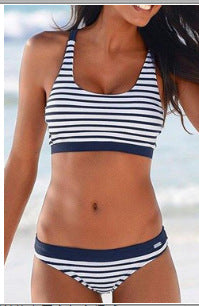 Woman smiling on a beach wearing a navy and white striped two-piece bikini with a racerback top. - Image 7