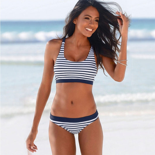 Woman smiling on a beach wearing a navy and white striped two-piece bikini with a racerback top. - Image 8