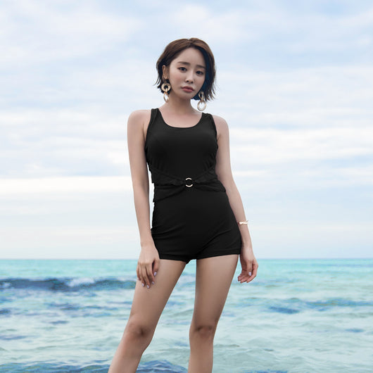 Woman in a mustard yellow one-piece swimsuit with a scalloped waist and short bottoms, standing in the ocean. - Image 4