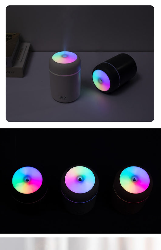 Dark gray cylindrical humidifier with colorful LED top light and thin light band, shown with five white filter sticks. - Image 13