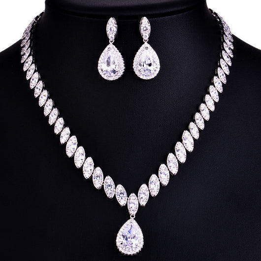 Silver-toned necklace and earring set with red teardrop stones and clear marquise-cut accents on a black display. - Image 11