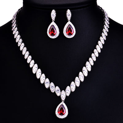 Silver-toned necklace and earring set with red teardrop stones and clear marquise-cut accents on a black display. - Image 12