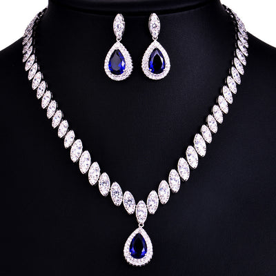 Silver-toned necklace and earring set with red teardrop stones and clear marquise-cut accents on a black display. - Image 13