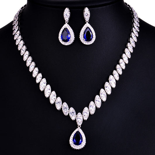 Silver-toned necklace and earring set with red teardrop stones and clear marquise-cut accents on a black display. - Image 13