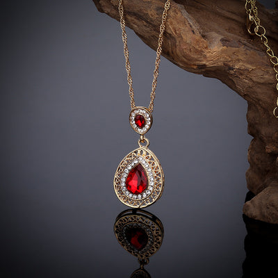 Gold-toned necklace and matching drop earrings set with blue teardrop crystals and clear rhinestones, on a wooden box. - Image 10