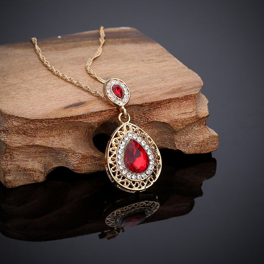 Gold-toned necklace and matching drop earrings set with blue teardrop crystals and clear rhinestones, on a wooden box. - Image 11