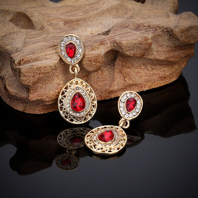 Gold-toned necklace and matching drop earrings set with blue teardrop crystals and clear rhinestones, on a wooden box. - Image 12