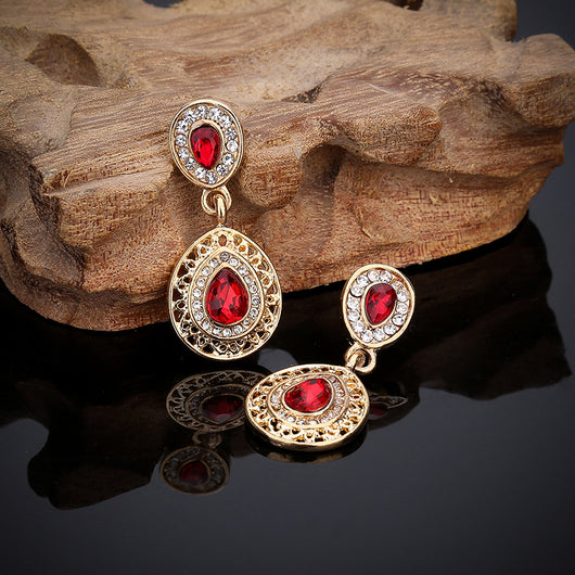 Gold-toned necklace and matching drop earrings set with blue teardrop crystals and clear rhinestones, on a wooden box. - Image 12