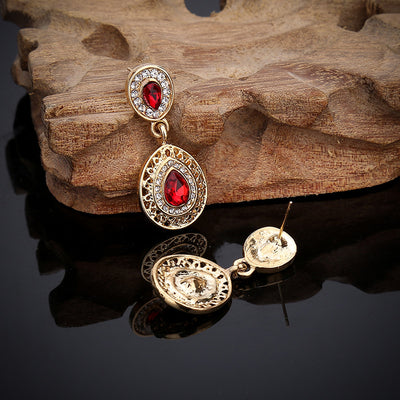Gold-toned necklace and matching drop earrings set with blue teardrop crystals and clear rhinestones, on a wooden box. - Image 13