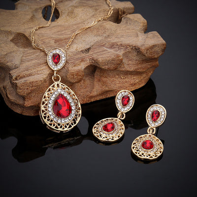 Gold-toned necklace and matching drop earrings set with blue teardrop crystals and clear rhinestones, on a wooden box. - Image 14