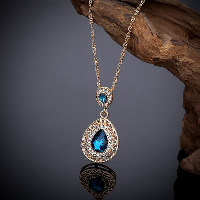 Gold-toned necklace and matching drop earrings set with blue teardrop crystals and clear rhinestones, on a wooden box. - Image 15