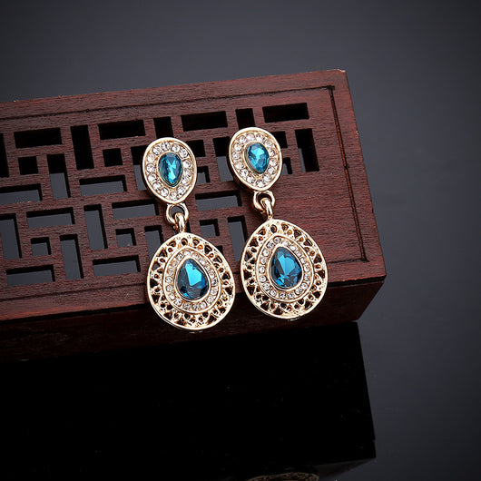 Gold-toned necklace and matching drop earrings set with blue teardrop crystals and clear rhinestones, on a wooden box. - Image 17