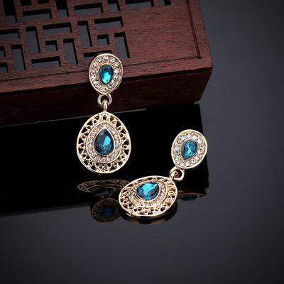 Gold-toned necklace and matching drop earrings set with blue teardrop crystals and clear rhinestones, on a wooden box. - Image 18