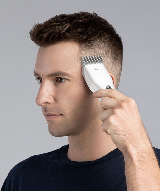 Black cordless hair shaver with a comb attachment and two white indicator lights, with a blurred white shaver in the background. - Image 10