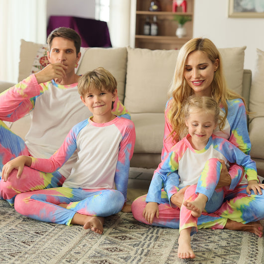 Family of four wearing matching pink, blue, and yellow tie-dye long-sleeved pajama sets in a living room. - Image 10