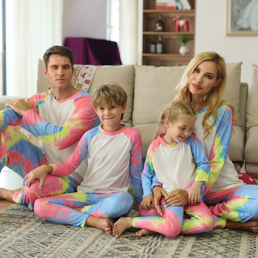 Family of four wearing matching pink, blue, and yellow tie-dye long-sleeved pajama sets in a living room. - Image 11