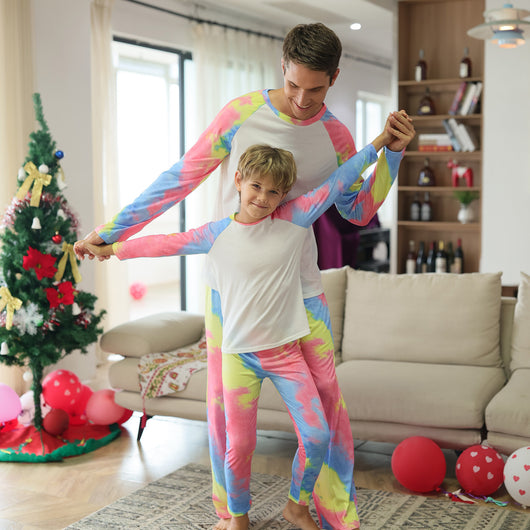Family of four wearing matching pink, blue, and yellow tie-dye long-sleeved pajama sets in a living room. - Image 14