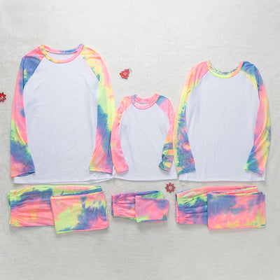 Family of four wearing matching pink, blue, and yellow tie-dye long-sleeved pajama sets in a living room. - Image 17