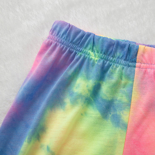 Family of four wearing matching pink, blue, and yellow tie-dye long-sleeved pajama sets in a living room. - Image 20