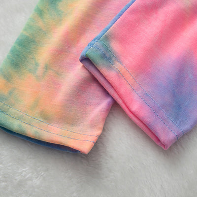 Family of four wearing matching pink, blue, and yellow tie-dye long-sleeved pajama sets in a living room. - Image 21