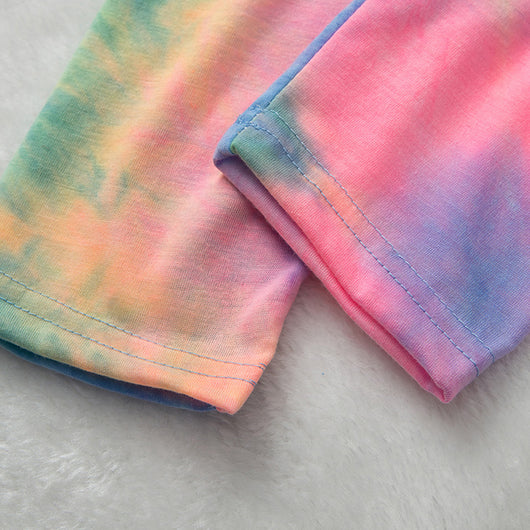 Family of four wearing matching pink, blue, and yellow tie-dye long-sleeved pajama sets in a living room. - Image 21