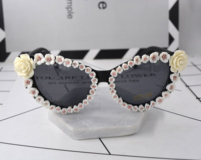 Black cat-eye sunglasses with dark lenses, adorned with small red rose embellishments along the frames. - Image 5