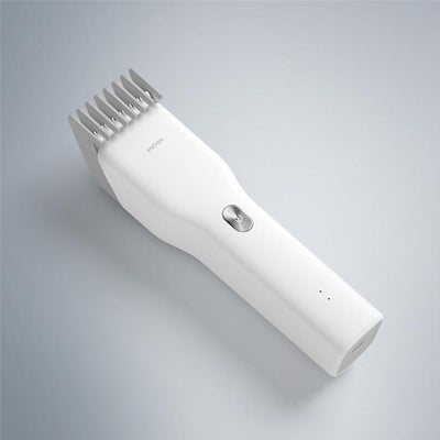 Black cordless hair shaver with a comb attachment and two white indicator lights, with a blurred white shaver in the background. - Image 7