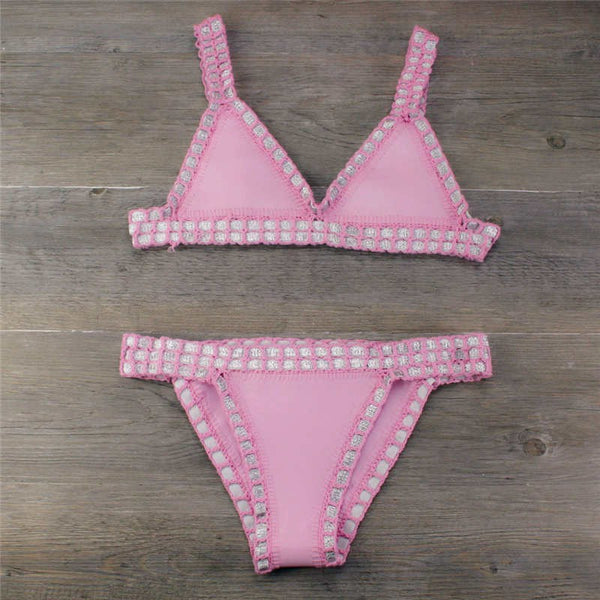 Pink crocheted bikini with silver knitted stitching, featuring a triangle top and matching bottom, laid flat.