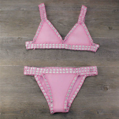 Pink crocheted bikini with silver knitted stitching, featuring a triangle top and matching bottom, laid flat.