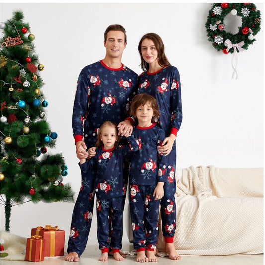 Family of four wearing matching navy blue Christmas pajamas with Santa Claus and snowflake print, red trim.