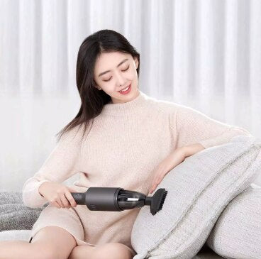 Dark gray cylindrical handheld vacuum cleaner in a car's cup holder, ready for quick interior cleaning.
