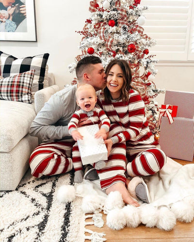 Family of three in matching red and white striped Christmas pajamas, posing for a mirror selfie in a festive living room. - Image 3