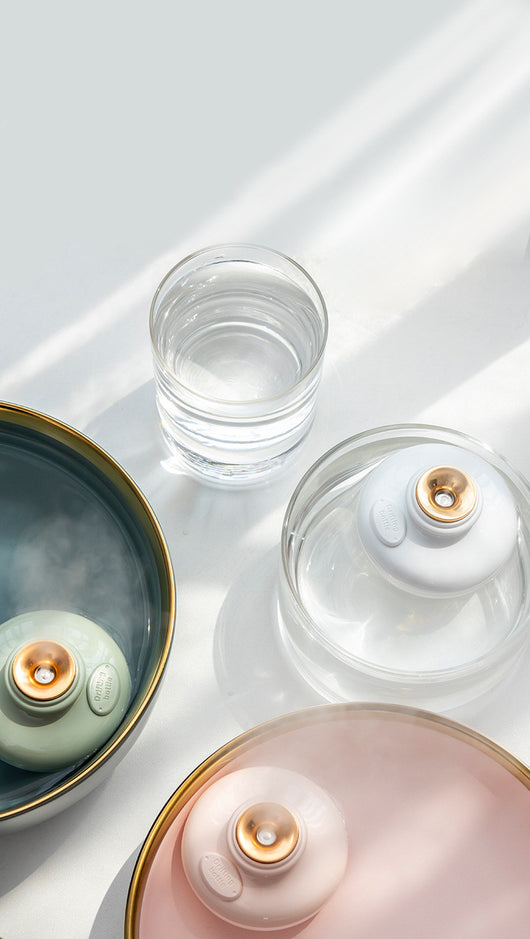 Three 'Drift bottle' humidifiers in white, mint green, and pink, floating in water and emitting mist. - Image 3