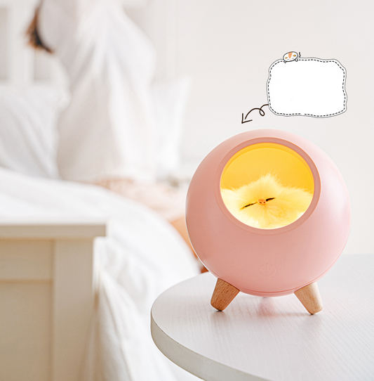 Pink spherical sleeping light with a sleeping cat design, wooden legs, and soft glow, displayed with gift packaging.