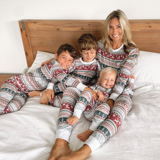 Family of seven wearing matching red and white Christmas pajamas with reindeer and snowflake patterns in a living room. - Image 17