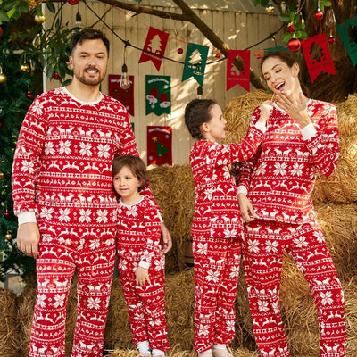Family of four wearing matching red and white Christmas pajamas with reindeer and snowflake patterns, smiling. - Image 11