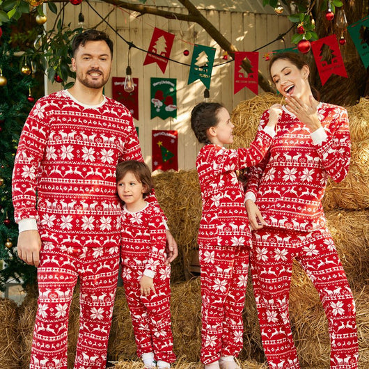 Family of four wearing matching red and white Christmas pajamas with reindeer and snowflake patterns, smiling. - Image 11