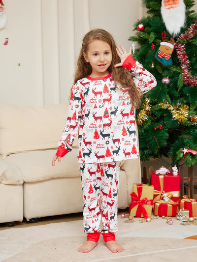 Young girl in white Christmas pajamas with red deer and tree print, red trim, standing by a decorated tree. - Image 10