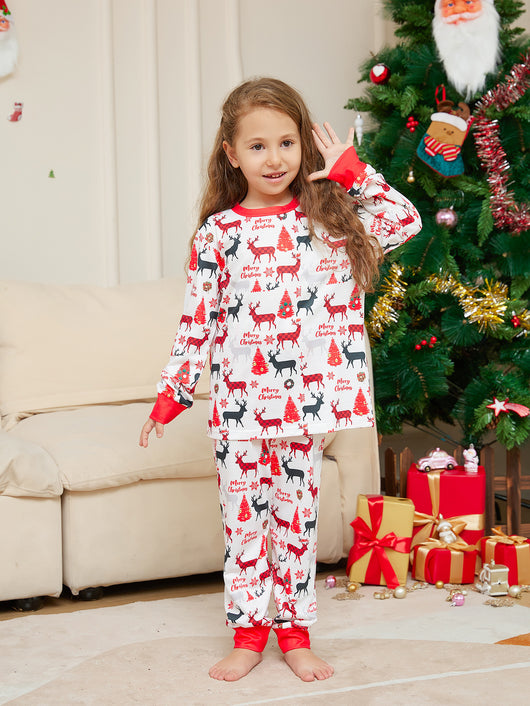 Young girl in white Christmas pajamas with red deer and tree print, red trim, standing by a decorated tree. - Image 10