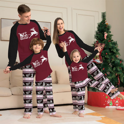 Child wearing a Christmas pajama set with a maroon and black reindeer top and black, pink, and white striped pants. - Image 9