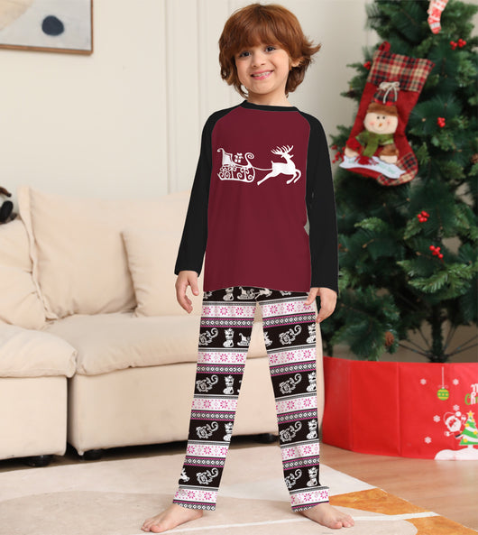 Child wearing a Christmas pajama set with a maroon and black reindeer top and black, pink, and white striped pants. - Image 11