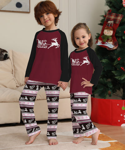 Child wearing a Christmas pajama set with a maroon and black reindeer top and black, pink, and white striped pants. - Image 12